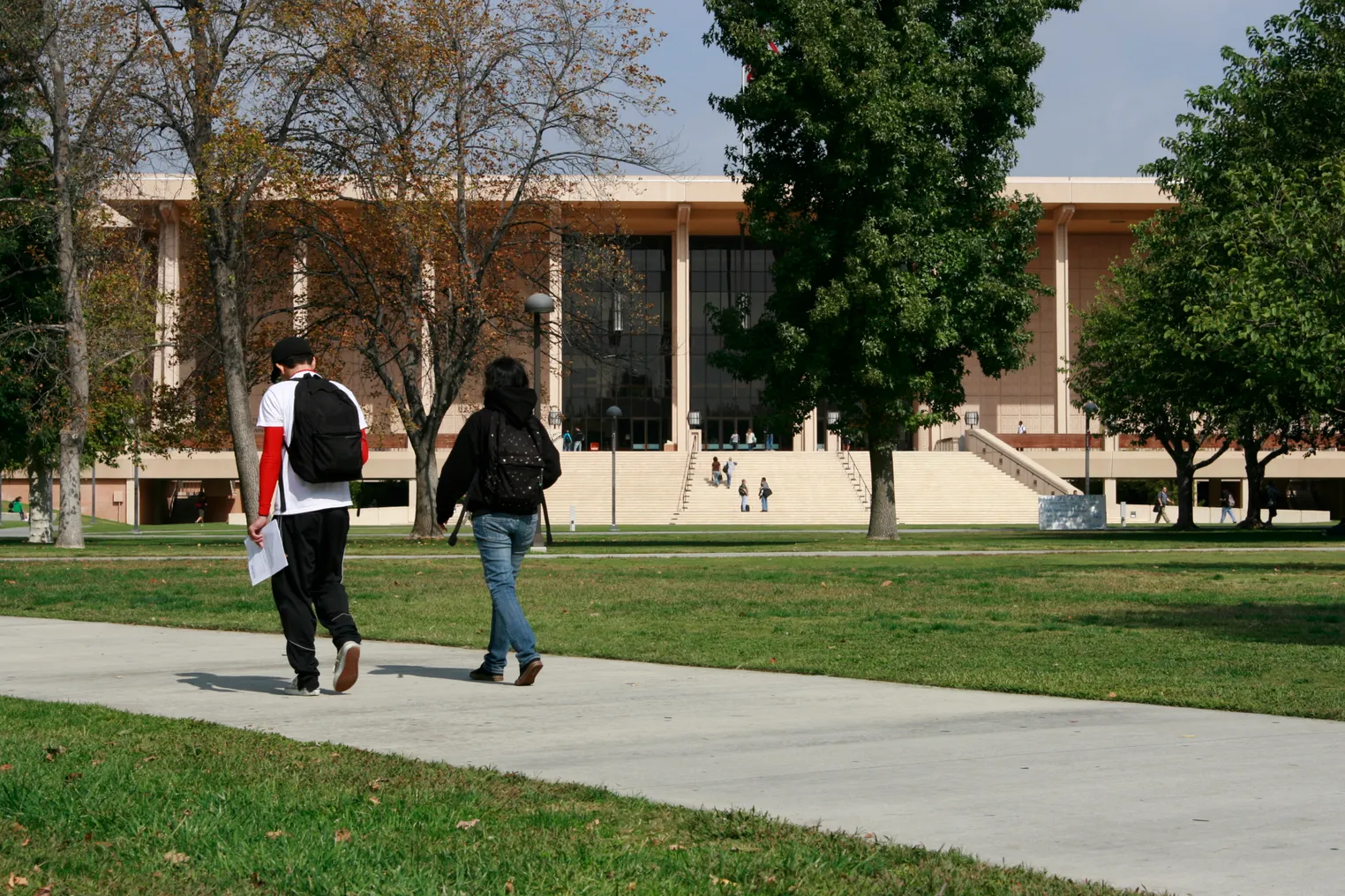 Students walking to class on CSUN campus with academic building in background.