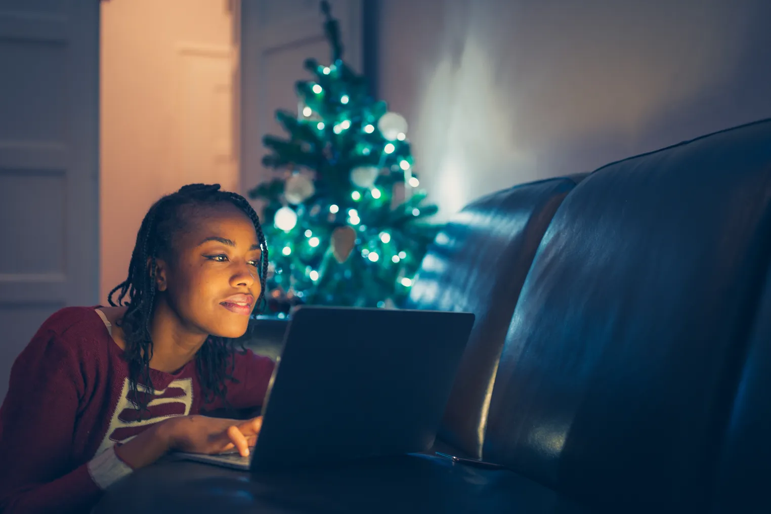 Person shops online with a Christmas tree in the background.