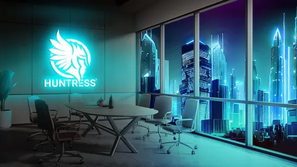 The Huntress cybersecurity company logo is picture on the way in an office overlooking a futuristic cityscape.
