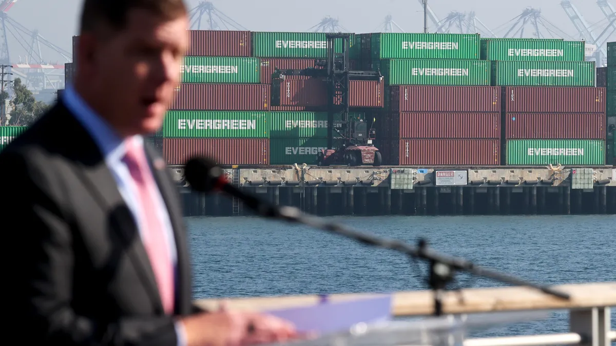 Shipping containers are shown stacked as U.S. Secretary of Labor Marty Walsh speaks at a press conference after touring the Port of Los Angeles on November 30, 2021