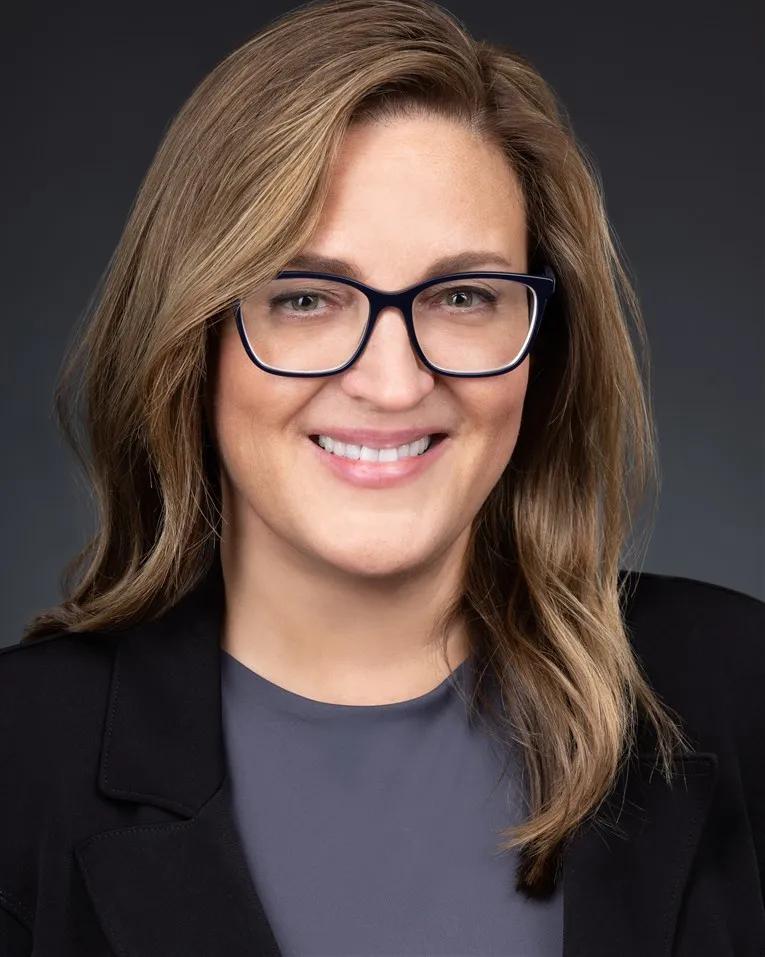 Headshot of Kate Mora, a white woman with dirty blonde hair and black glasses