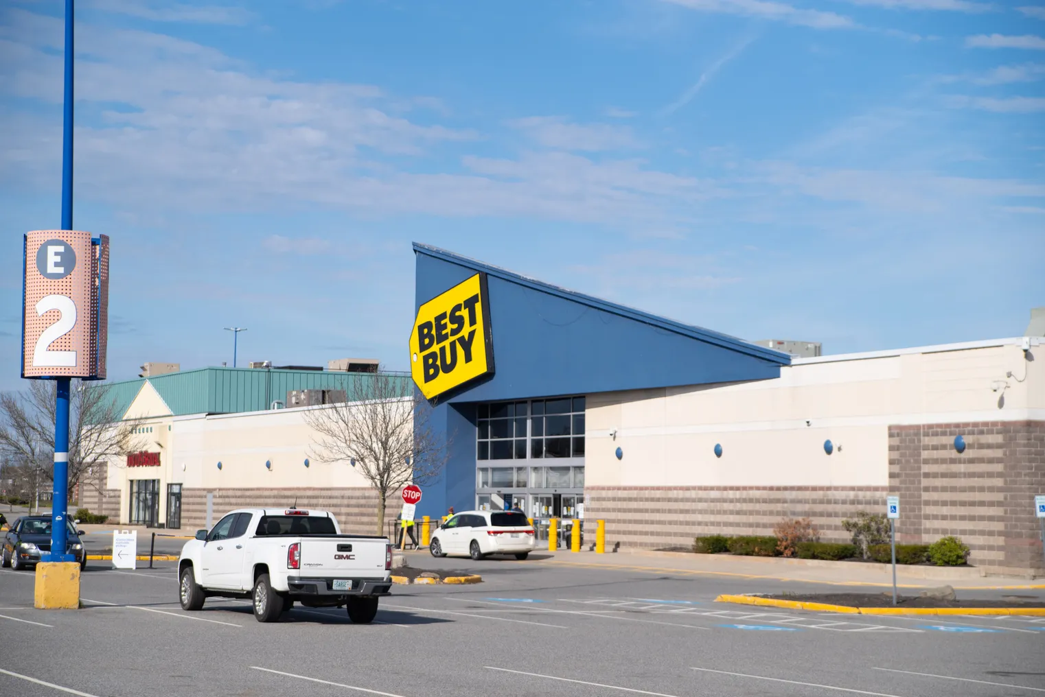 A bright yellow sign against a blue roof says "Best Buy" in bold black letters.