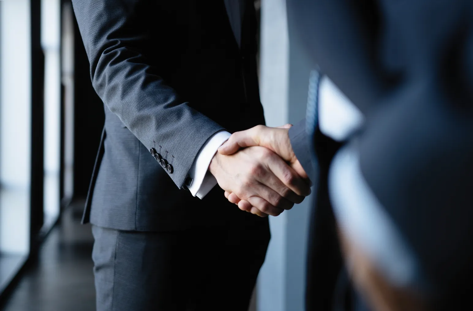 Two businesses executives shake hands in office