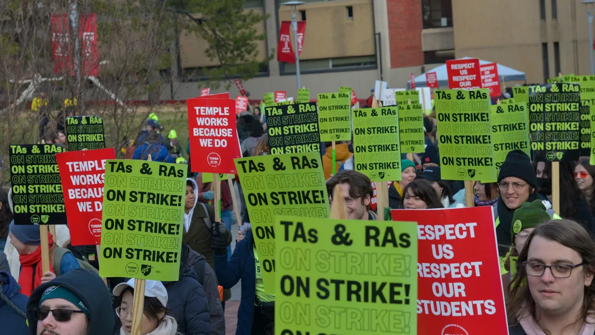 Dozens of people in winter clothing carry protest signs that say "TAs and RAs on strike!"