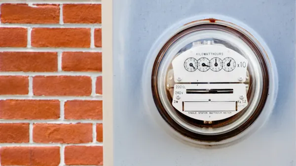 An energy meter displaying usage in kilowatt-hours is seen next to a brick wall
