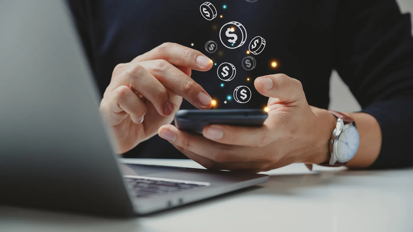 Hand of person tapping phone with dollar signs floating up