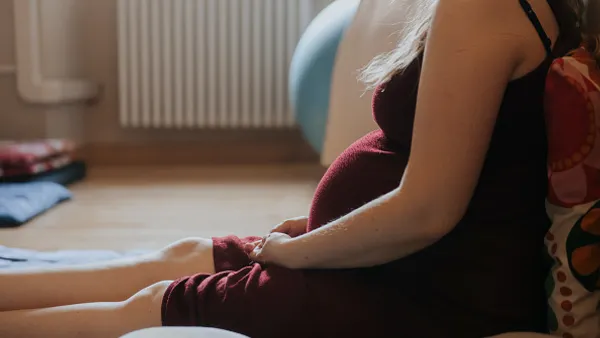 A pregnant woman sits on the floor