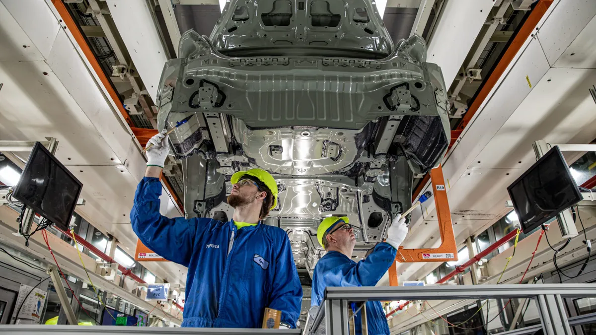 Two workers inspect a vehicle body on the assembly line at Toyota Motor Manufacturing Kentucky.