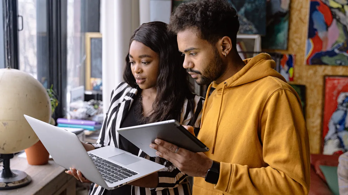 Two people are talking in an office & looking at a laptop