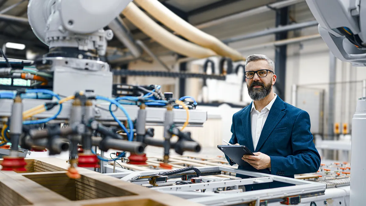 Man standing in a manufacturing facility with robotics and automation