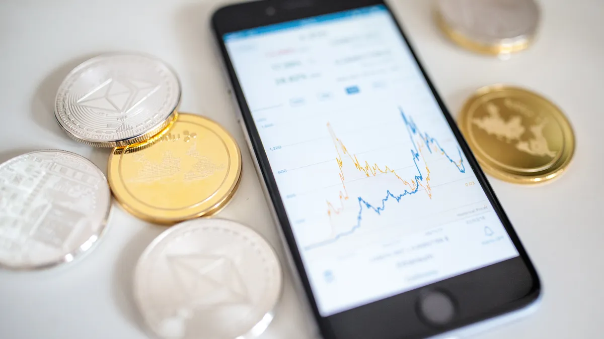 Cryptocurrency coins next to a smartphone displaying a chart