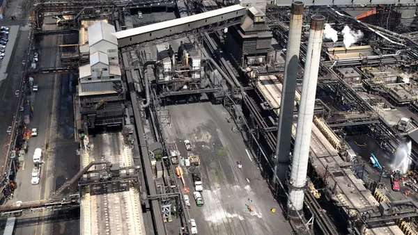 An overhead exterior view of a factory covered in black soot after an explosion.