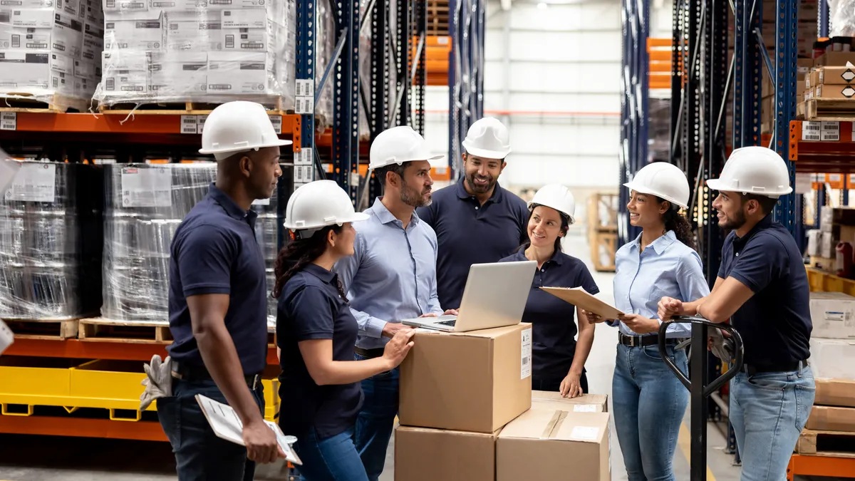 Business manager talking to a group of employees at a distribution warehouse - staff meeting concepts