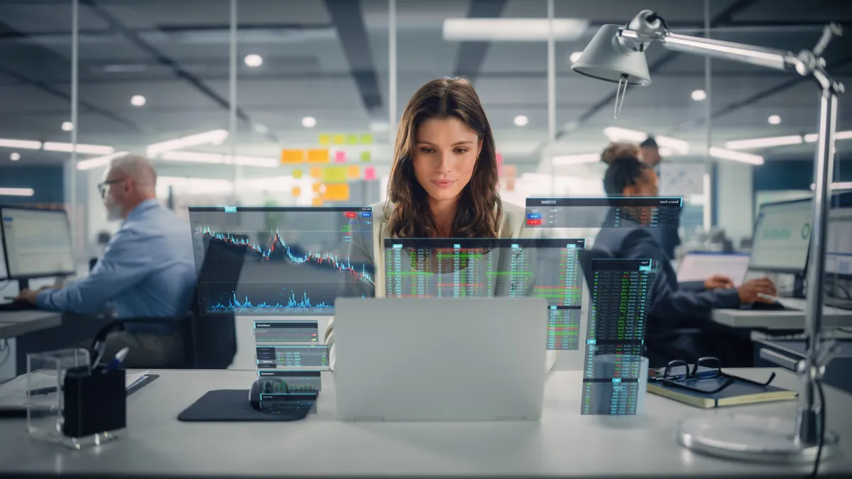 Young Happy Businesswoman Using Laptop Computer in Modern Office with Colleagues with VFX Hologram Edit Visualizing Stock Exchange Interface, Opened Charts.