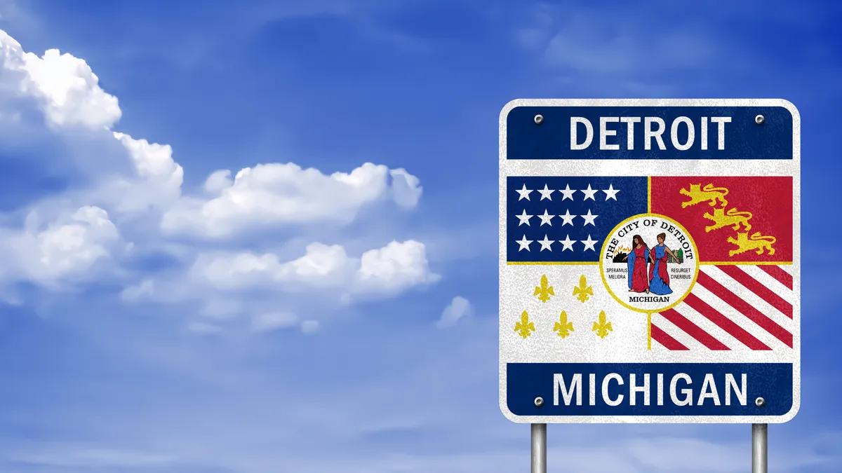 Detroit, Michigan sign on highway against blue sky backdrop.