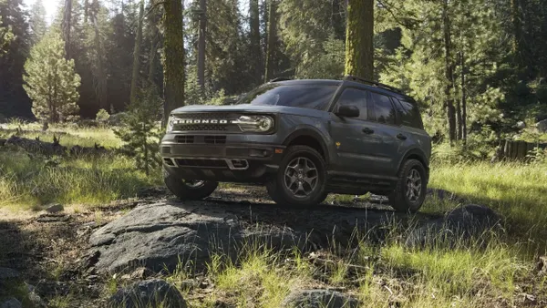 A media photo of a 2022 Ford Bronco Sport SUV on top of a large boulder in a wooded area outdoors.