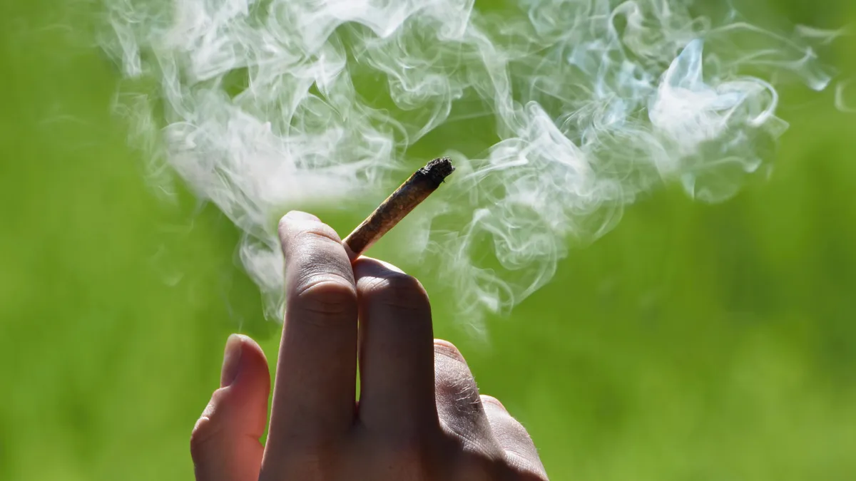 A person holds a smoking joint.