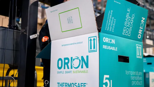 A fiber shipping box with blue and white Orion and ThermoSafe branding sits on a conveyor.