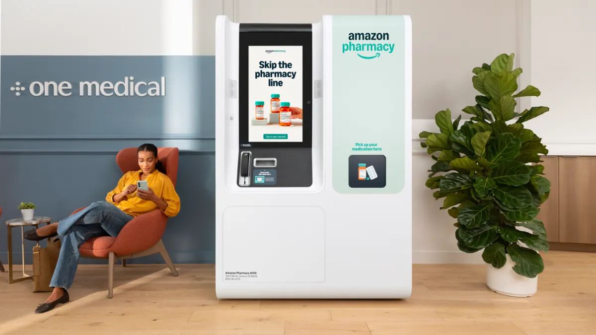 A woman using her phone sits next to an Amazon Pharamcy prescription kiosk.