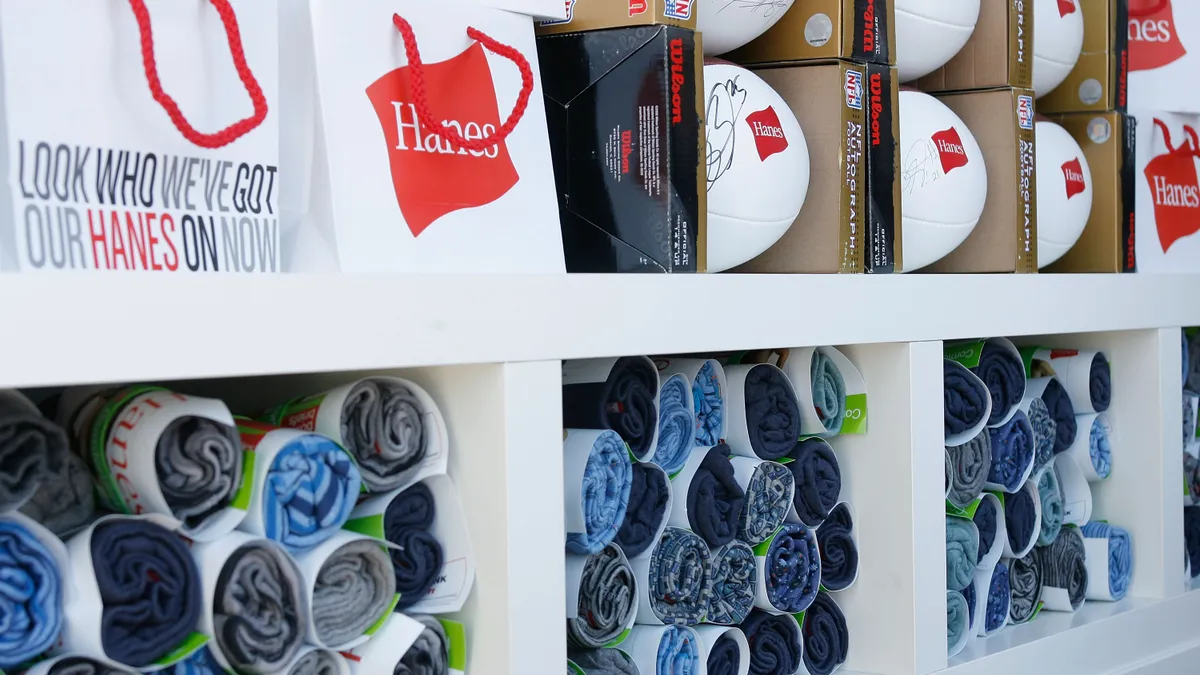 A HanesBrands store display is pictured, including paper bags, footballs and t-shirts, all with the Hanes logo.