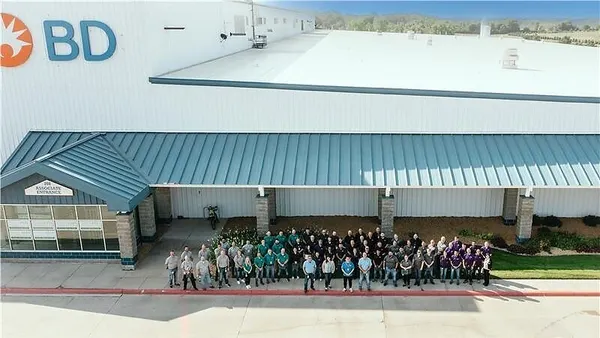 A large group of employees stand outside a facility.