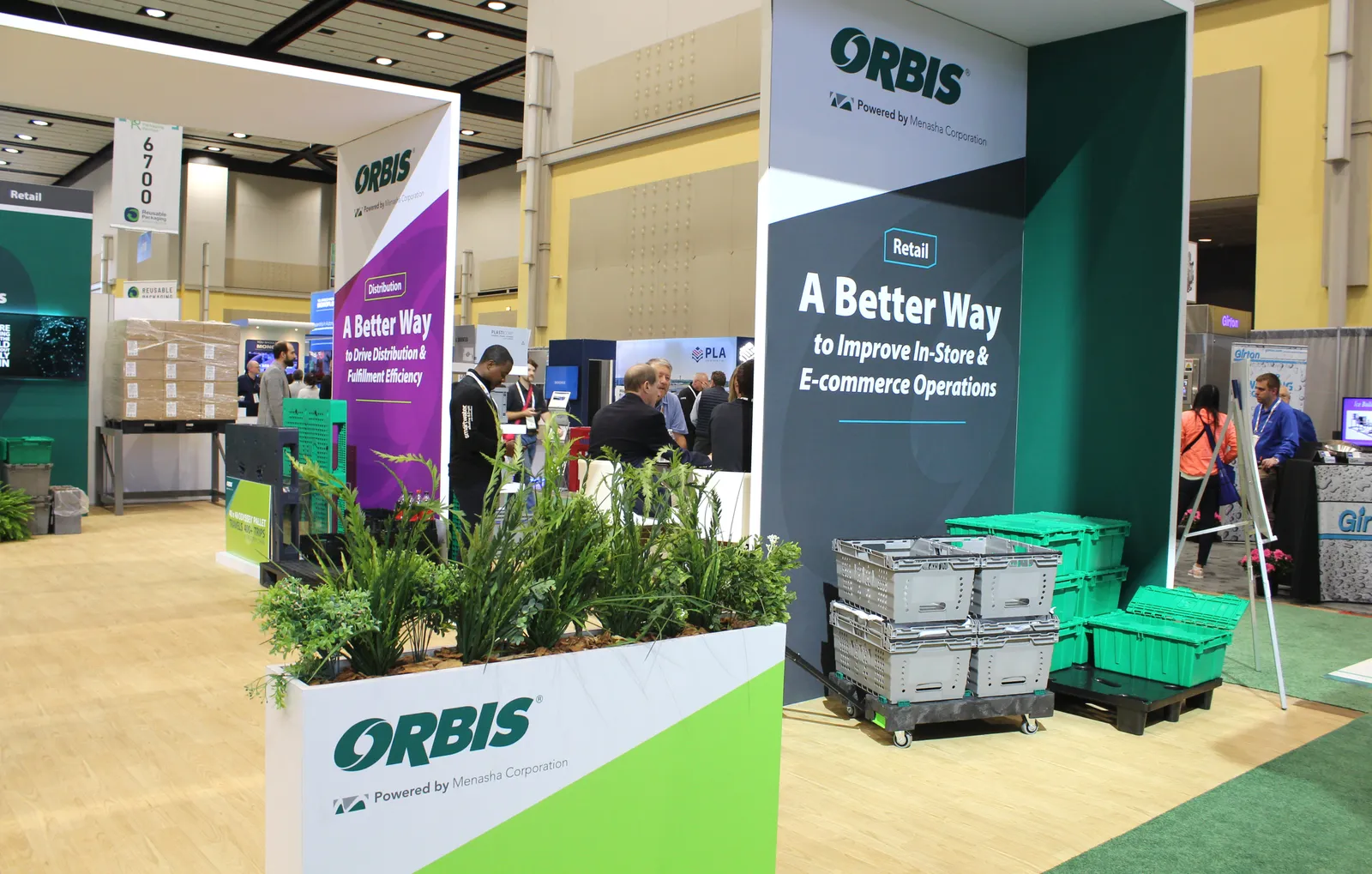 A company display at a conference showing reusable totes and Orbis branding.