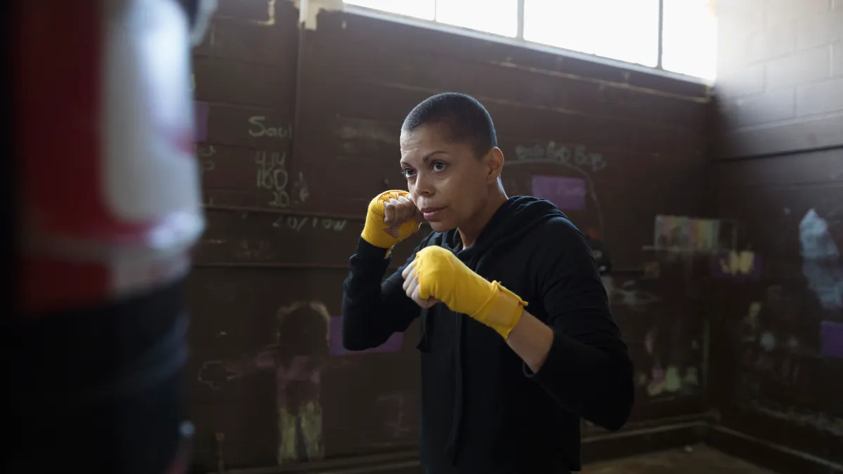 Boxer boxing at punching bag in gritty gym