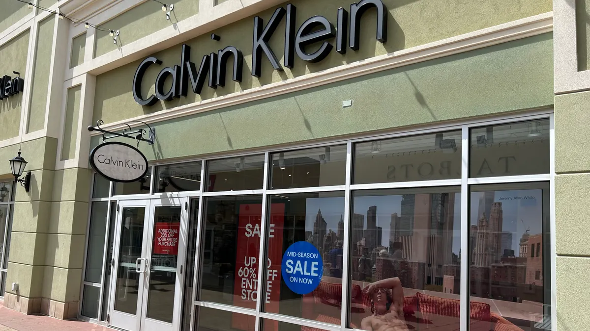 The exterior of a Calvin Klein store. The windows show signs for sales and an image of actor Jeremy Allen White wearing Calvin Klein underwear.