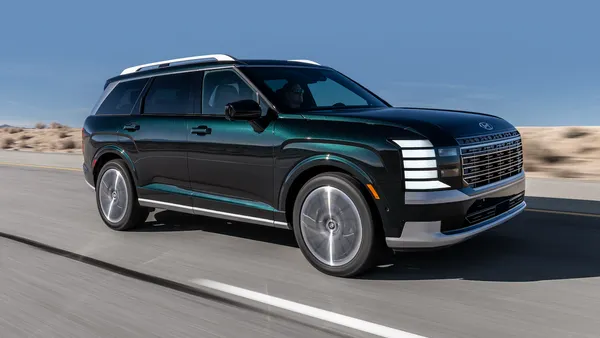 A 2027 Hyundai Palisade Hybrid Calligraphy SUV driving on a road with blue sky in the background.
