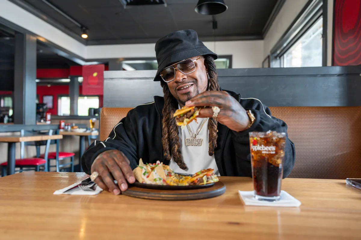 A person sits at a table in a restaurant and holds up a menu item.