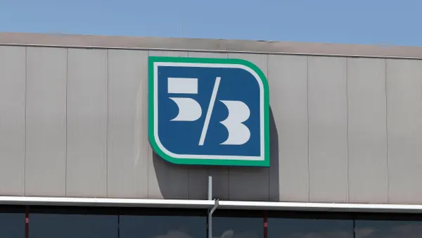 A large sign with the Fifth Third Bank logo on the side of a grey metal building, featuring a blue square with white and green outlines and a stylized "5/3" symbol inside.