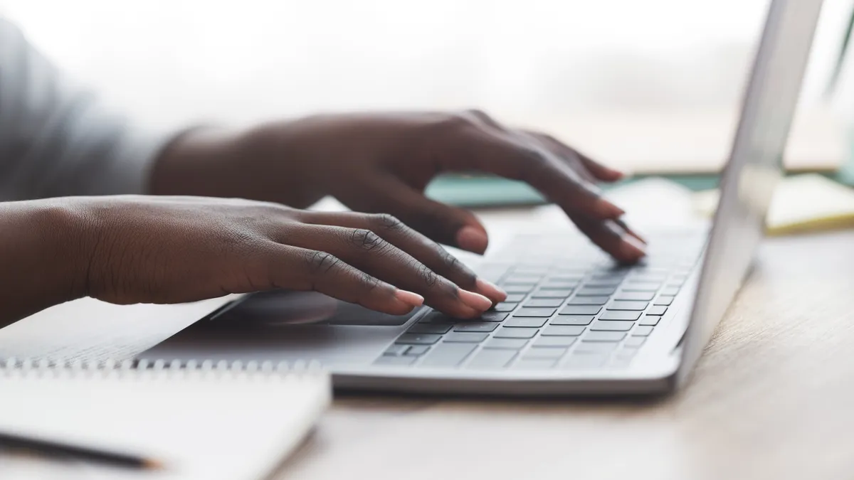 Hands type on a laptop keyboard.