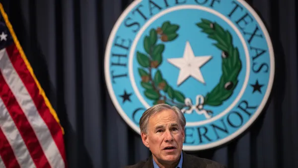 Texas Gov. Greg Abbott in front of a state sign