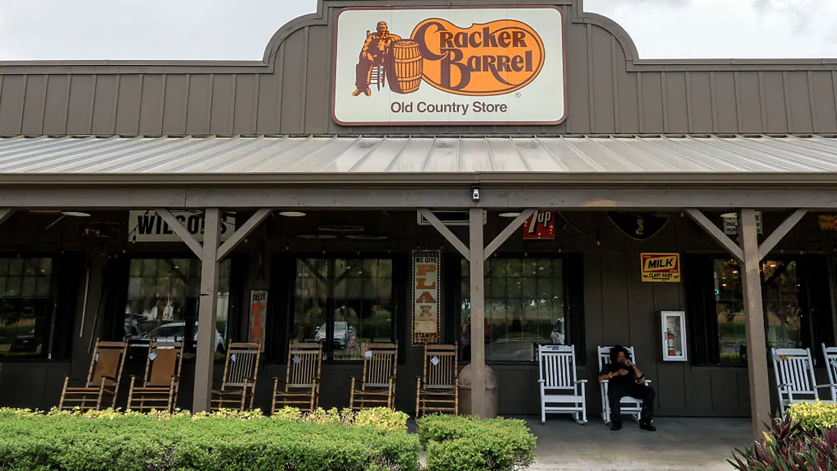 A Cracker Barrel sign hangs on the outside of a restaurant.