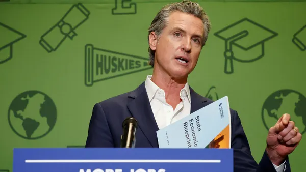 A man in a blue suit standing behind a podium with a blue book in his hand.