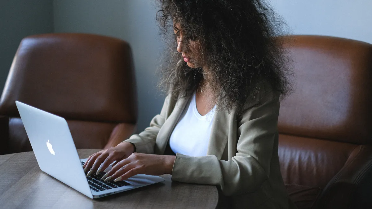 A young adult types on a laptop in an office