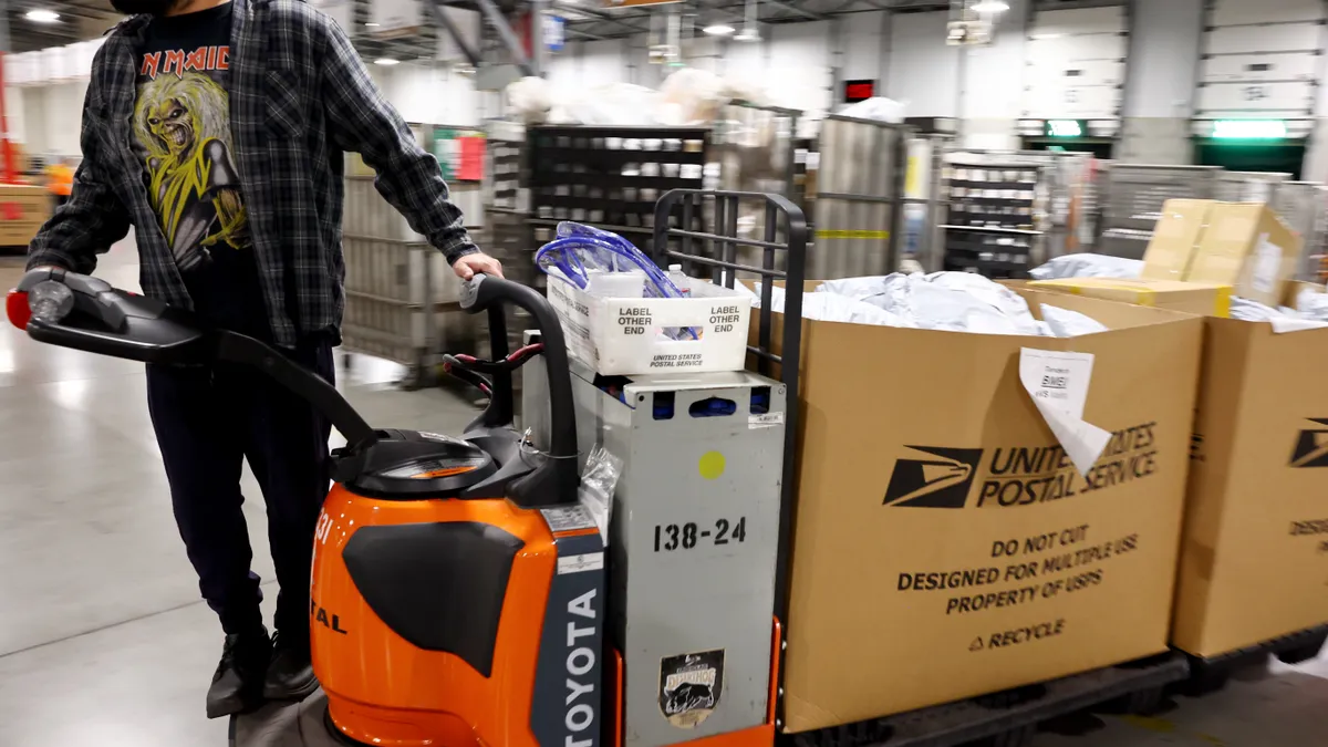 A U.S. Postal Service employee transports parcels for distribution ahead of the holiday mail rush inside the Los Angeles Processing and Distribution Center on November 30, 2022 in Los Angeles, Califor