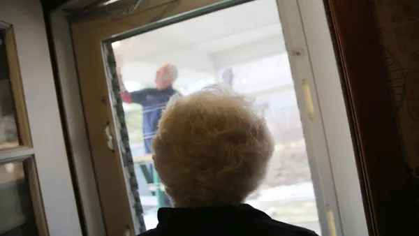 A technician replaces a light bulb outside a senior's home.