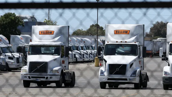 Yellow Corp. trucks sit at a company facility behind a fence in 2023.