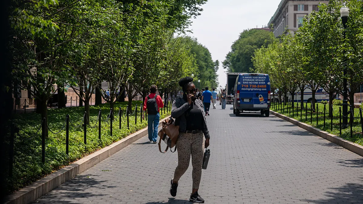 A person walks on a pathway at Columbia University talking on the phone.