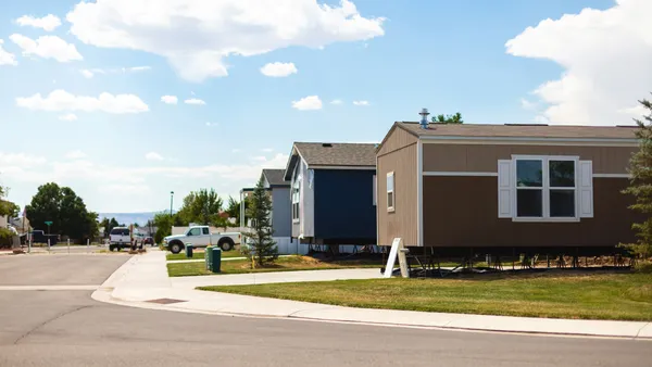 A street lined with trees, cars and manufactured homes