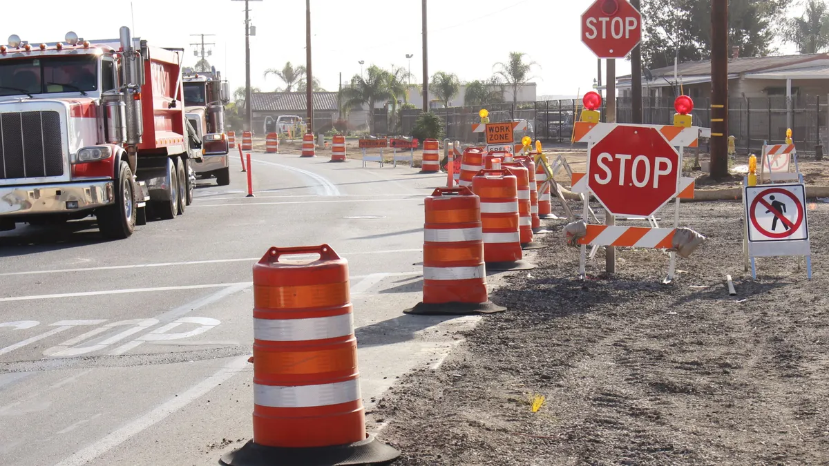 A series of cones and stop signs on a highway worksite.