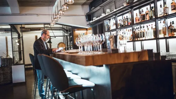 A man stands at a bar checking out.
