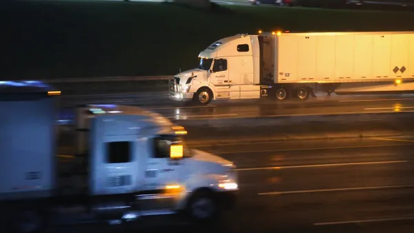 Two trucks pass each other at night on a rain-covered highway near Chicago.