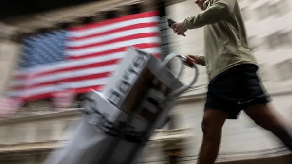 A delivery person looks at a phone while delivering boxes.