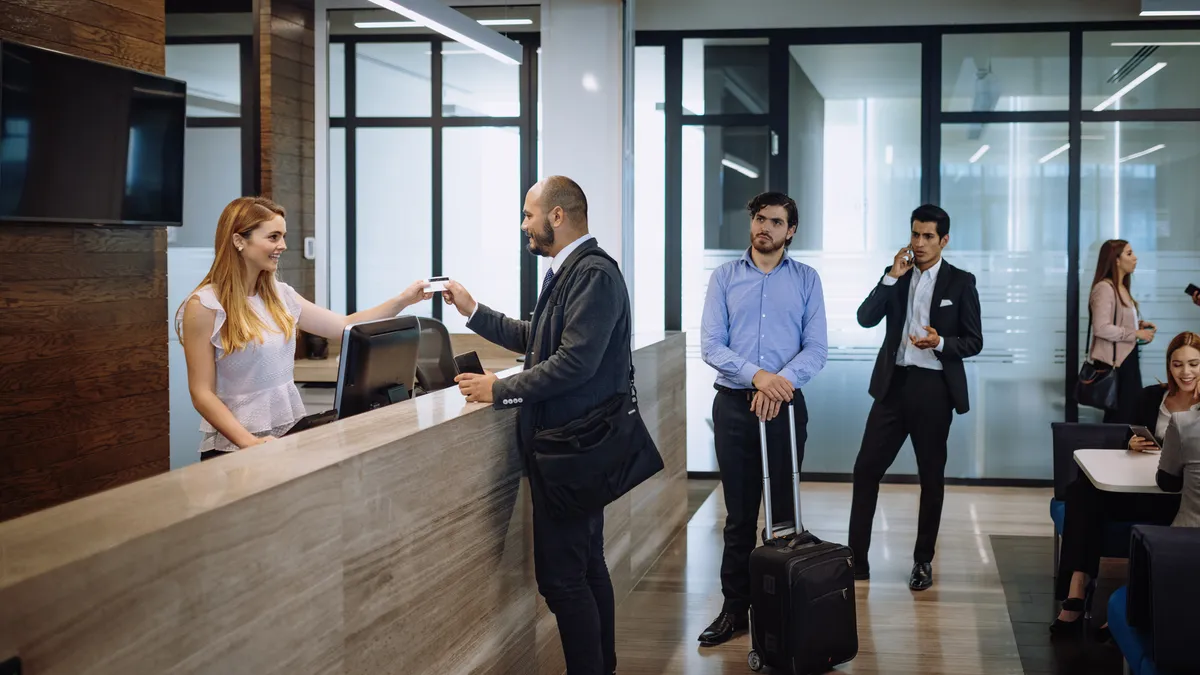 A business traveler check into a hotel in the hotel lobby.