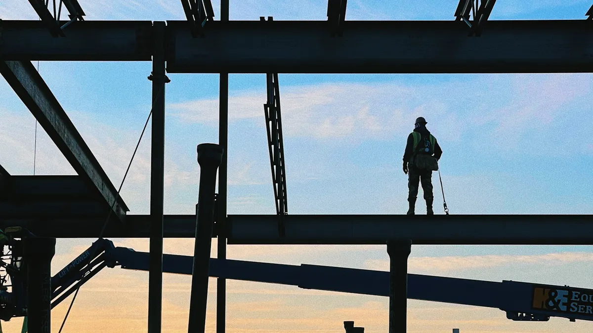 A worker, wearing fall prevention gear, looks over a Turner construction site.