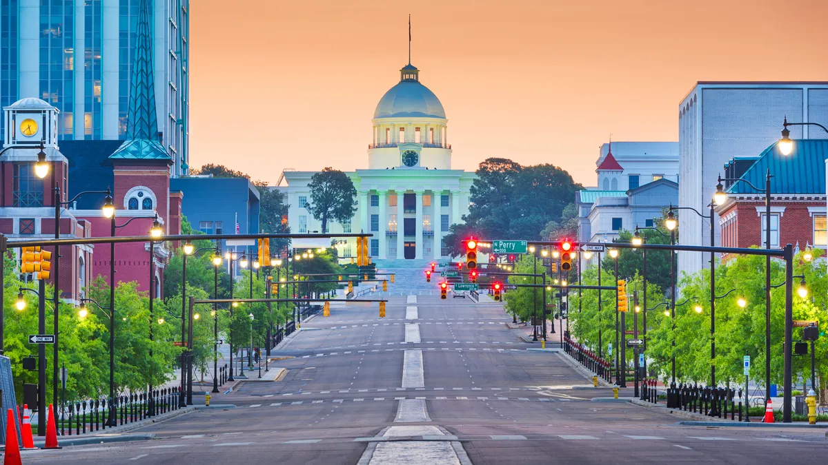 Montgomery, Alabama, with the state Capitol and city buildings at dawn. A series of traffic lights are all red.