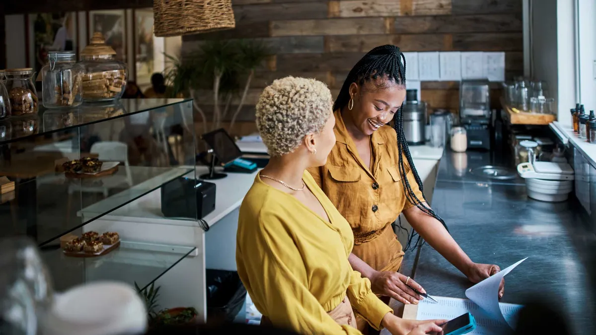Business owner training new employee on the job at a coffee shop.