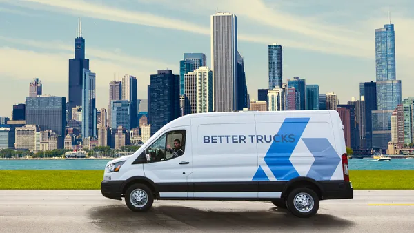 A driver gives a thumbs up in a Better Trucks delivery van.